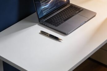 Pióro i laptop na czystym biurku symbolizujące styl pisania człowieka powtórzony przez AI.